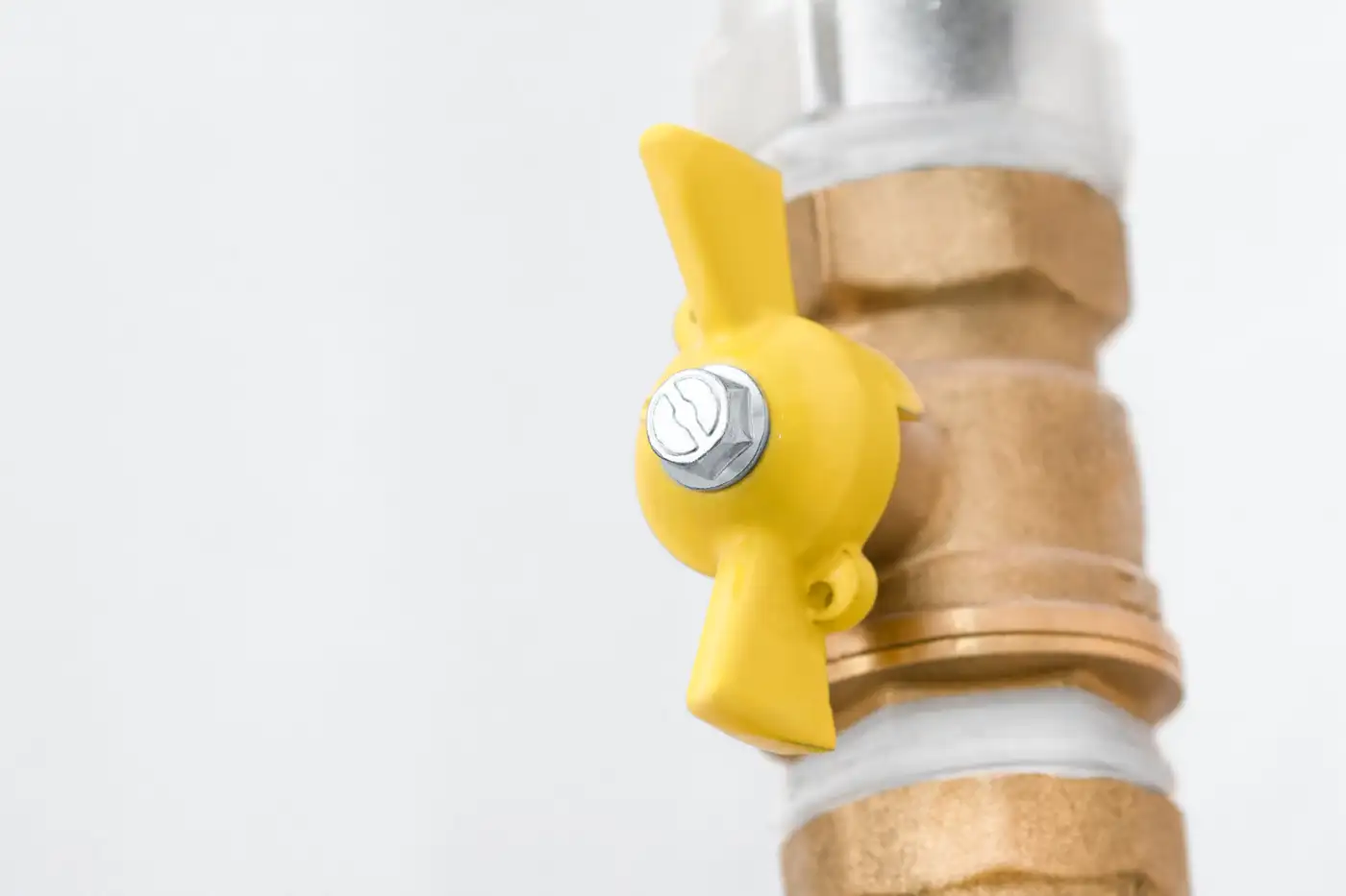 A yellow gas isolation valve on a brass gas pipe