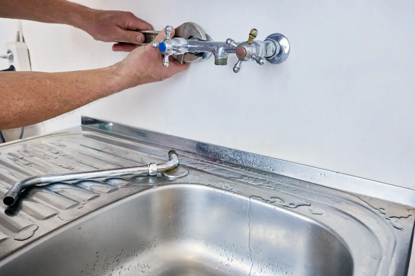 Turning off the water at the valves above a kitchen sink