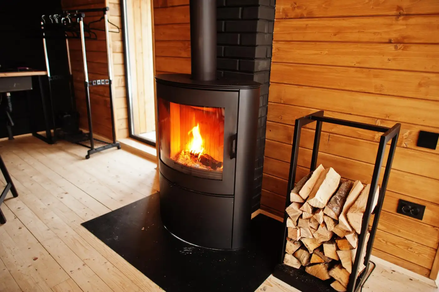 A carbon monoxide alarm fitted to the wall beside a wood-burning stove in a living room