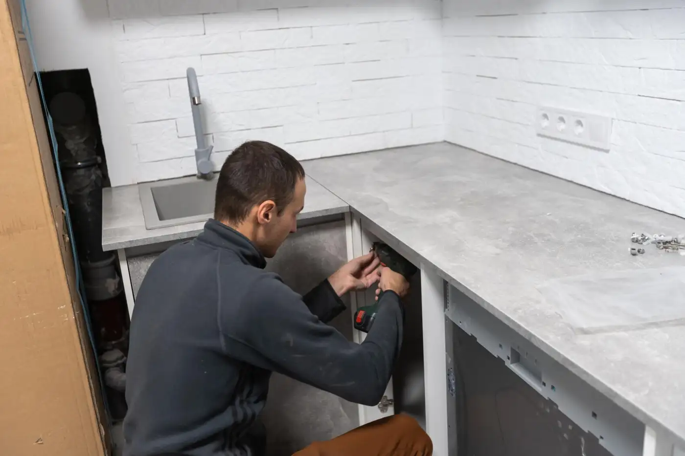 A kitchen fitter installing base units and a worktop during a kitchen renovation