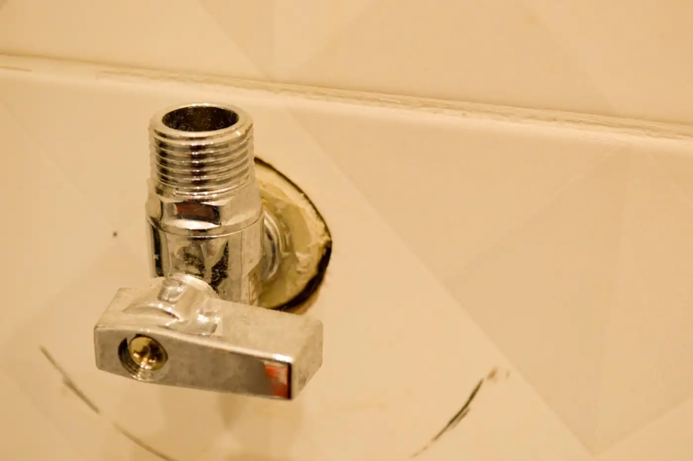 A slotted isolation valve on a copper supply pipe under a kitchen sink, turned across the pipe to shut off the water