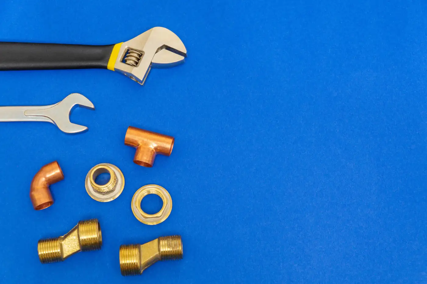 Plumbing tools and copper pipe fittings laid out on a workbench