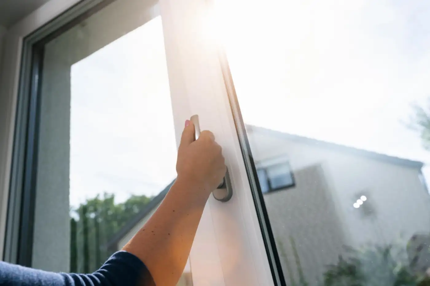 A hand opening a window to ventilate a room