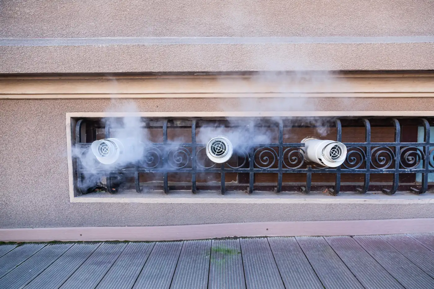 Flue terminals on the outside wall of a house with vapour rising