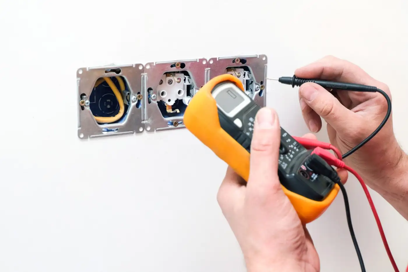 An electrician testing a wall socket with a multimeter