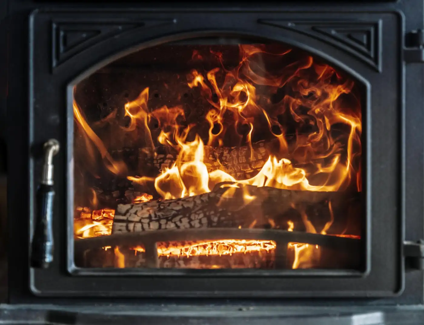 Logs burning behind the door of a wood-burning stove