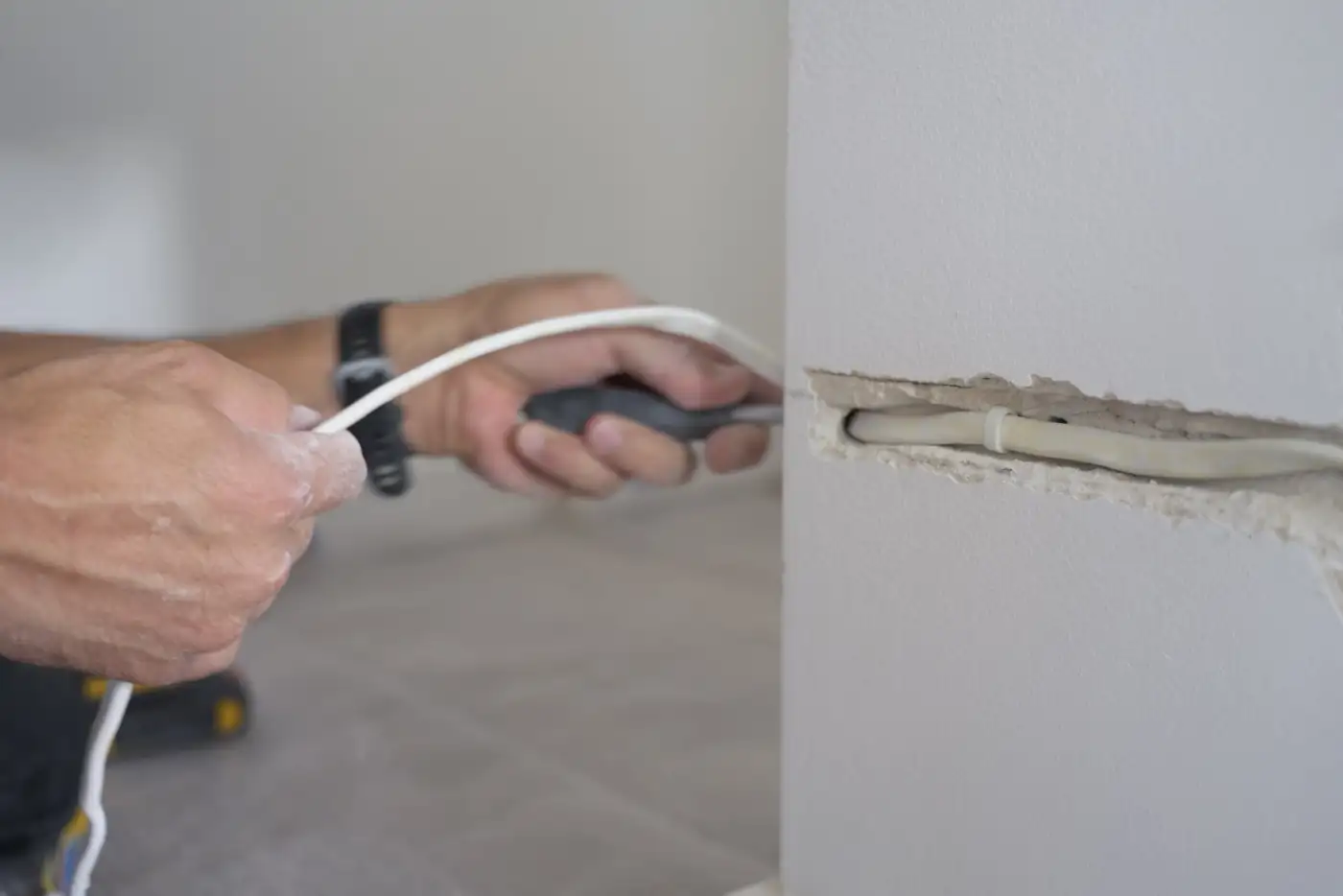 An electrician pulling cable through a channel chased into an interior wall