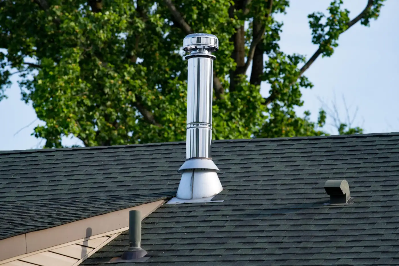 A stainless steel flue terminal passing through a house roof