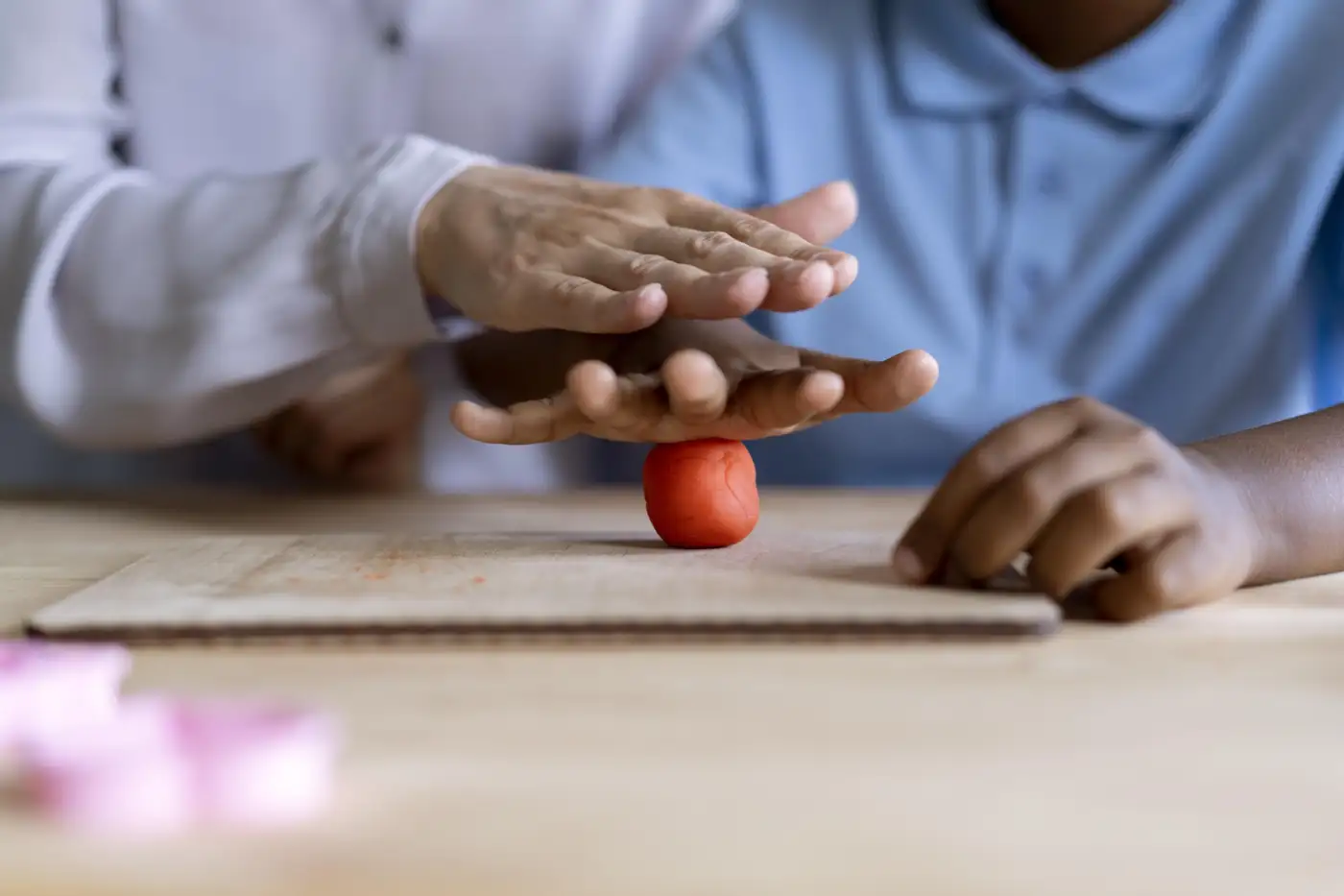 Close-up of hands during an occupational therapy exercise with a small ball on a table