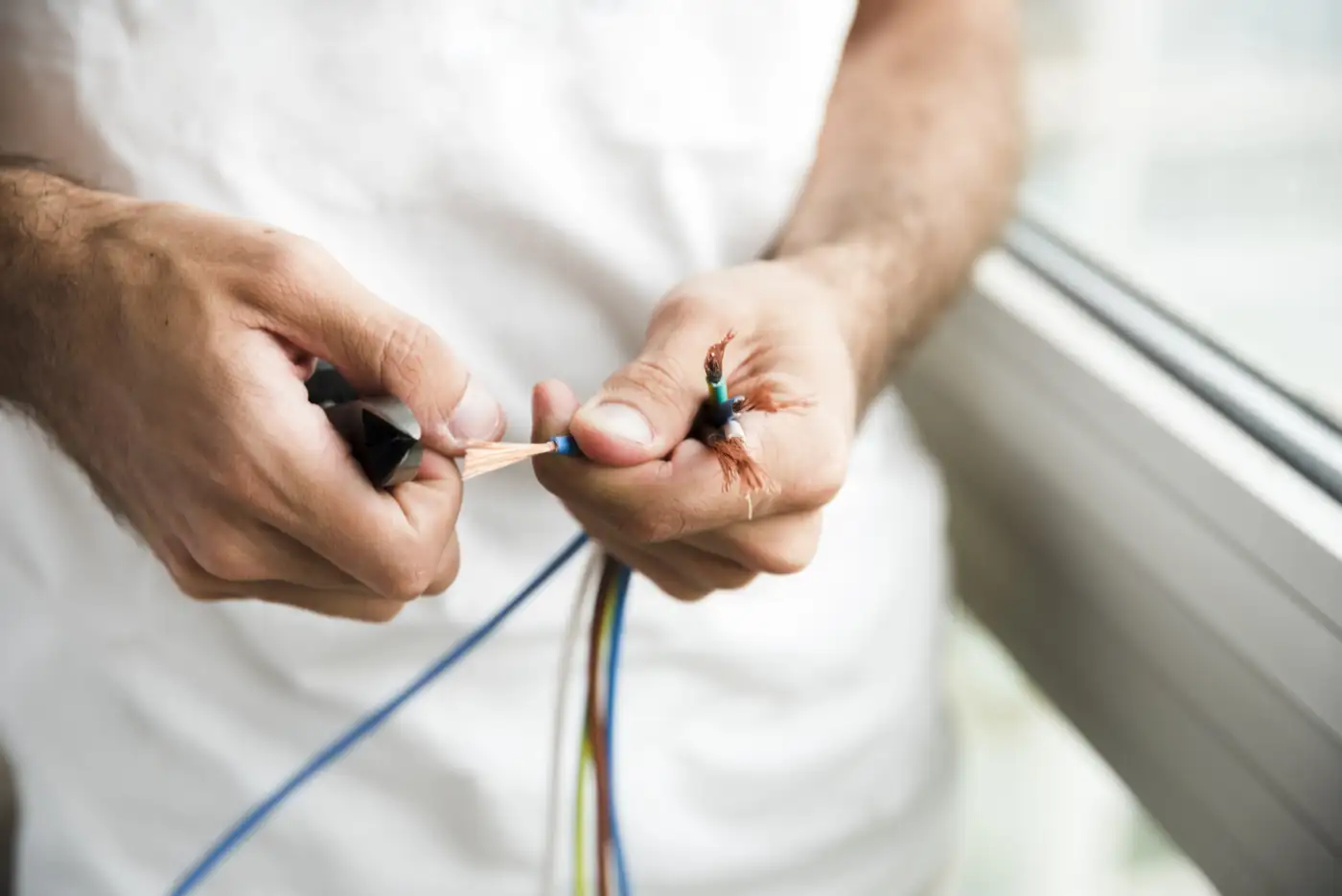 Close-up of electrician removing plastic coating from electrical cable