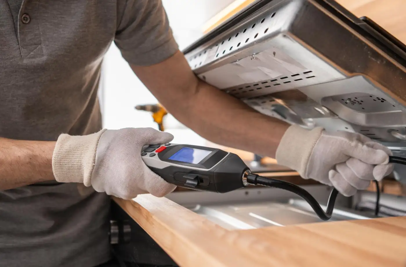 Kitchen appliances installer checking for gas leaks with a handheld detector