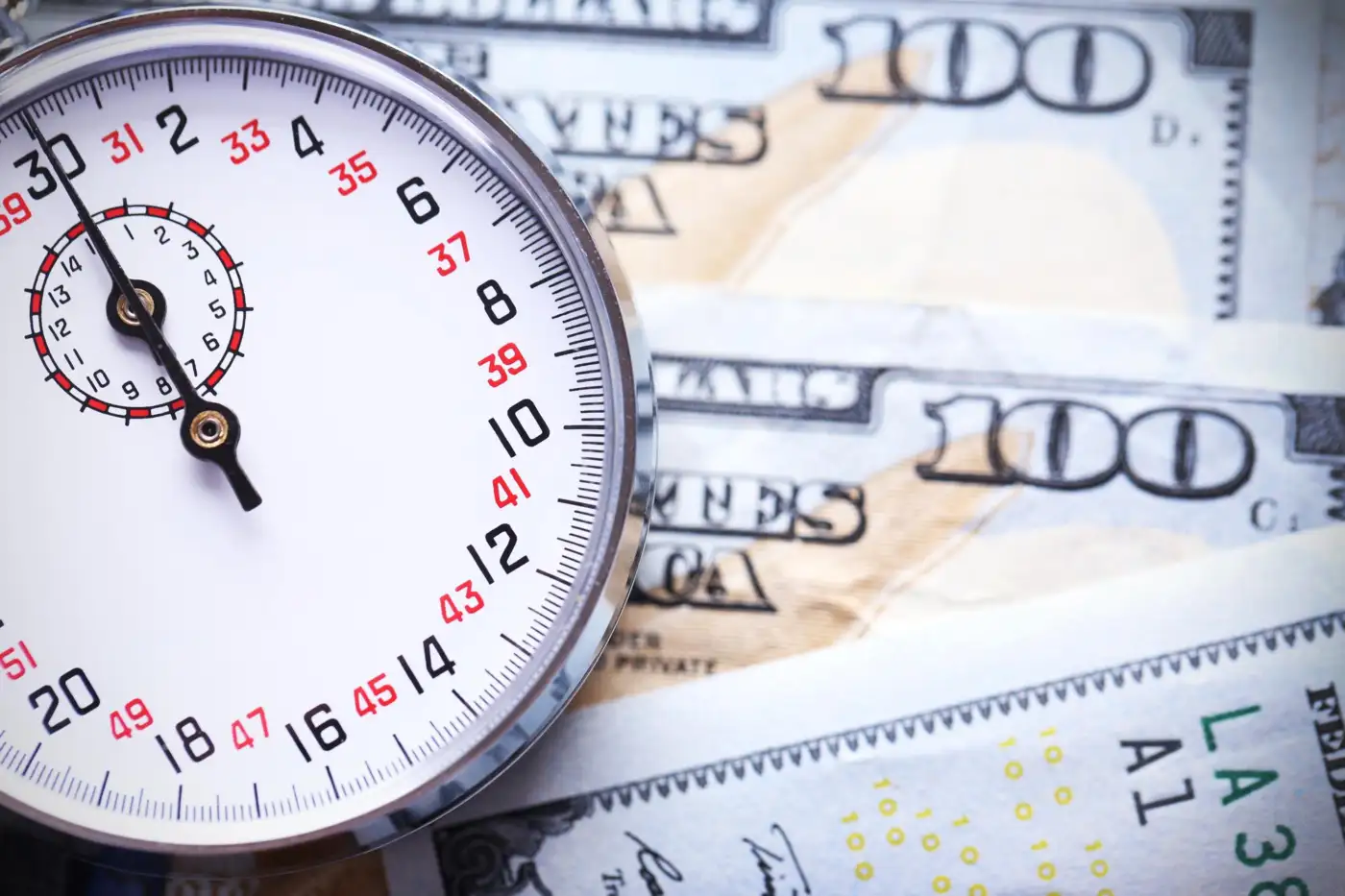 Stopwatch and banknotes in close-up photograph representing time-is-money concept